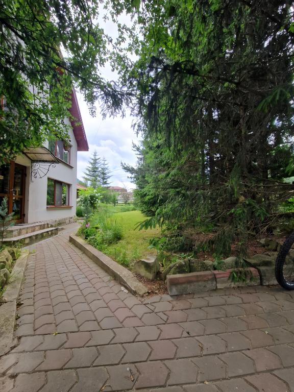 a brick walkway next to a house with a tree at Pensiunea Rossvillas!! in Lepşa