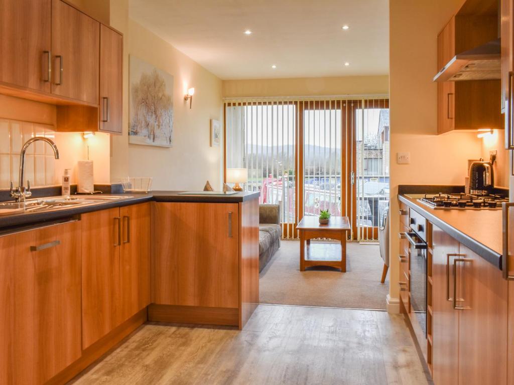 a kitchen with wooden cabinets and a living room at Swan House in Carnforth