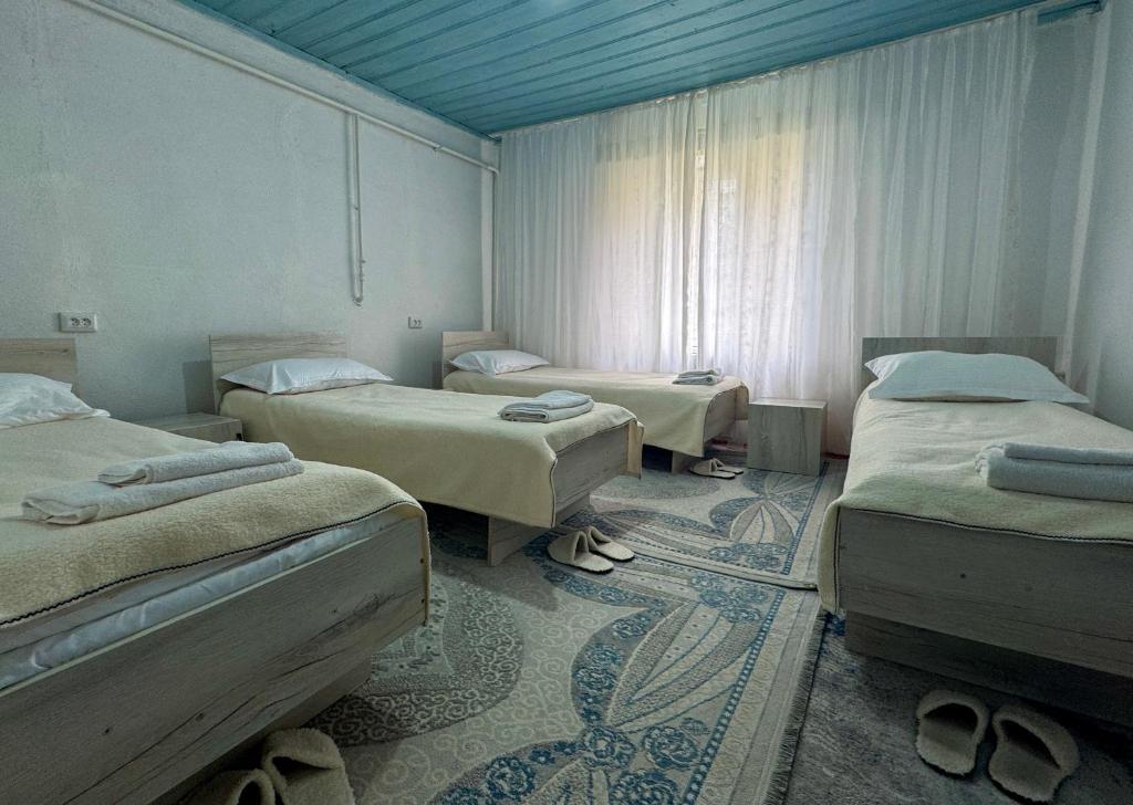a room with three beds and shoes in it at "AlmUrUt" Guest House in Bokonbayevo