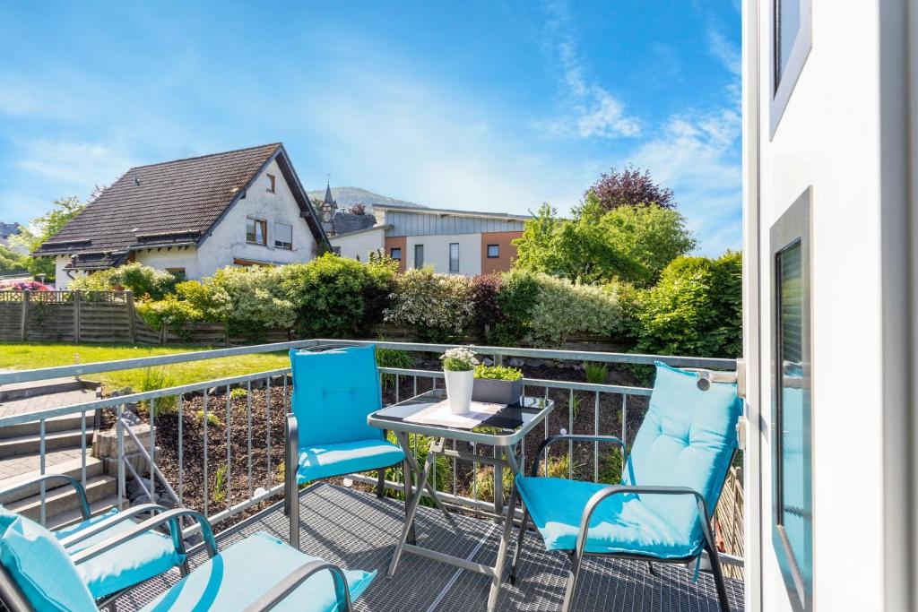 a balcony with blue chairs and a table at Ferienwohnung Coerdt Sauerland in Olsberg