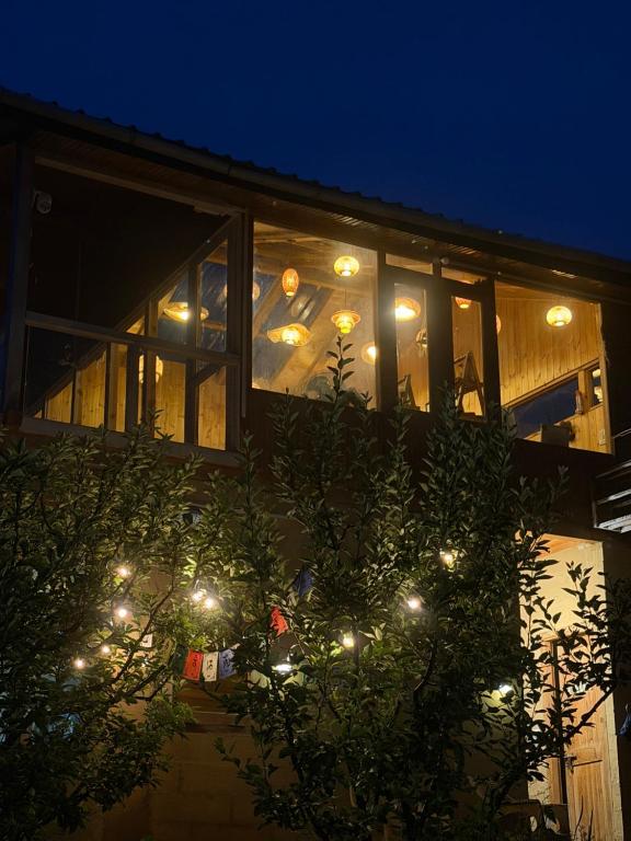 a house with lights in the window at night at Baserah - Cafe & Stay in Jibhi