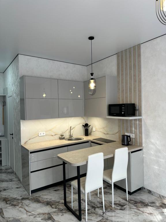 a kitchen with a table and two white chairs at SmartStudio in Odesa