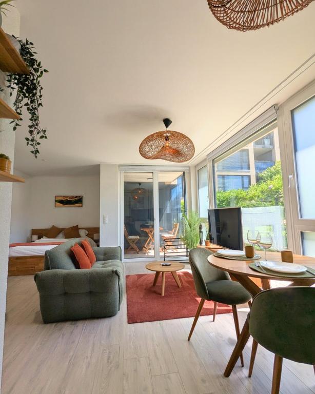 a living room with a bed and a table and chairs at Studio Premium - Jardin privatif - Parking in Epalinges