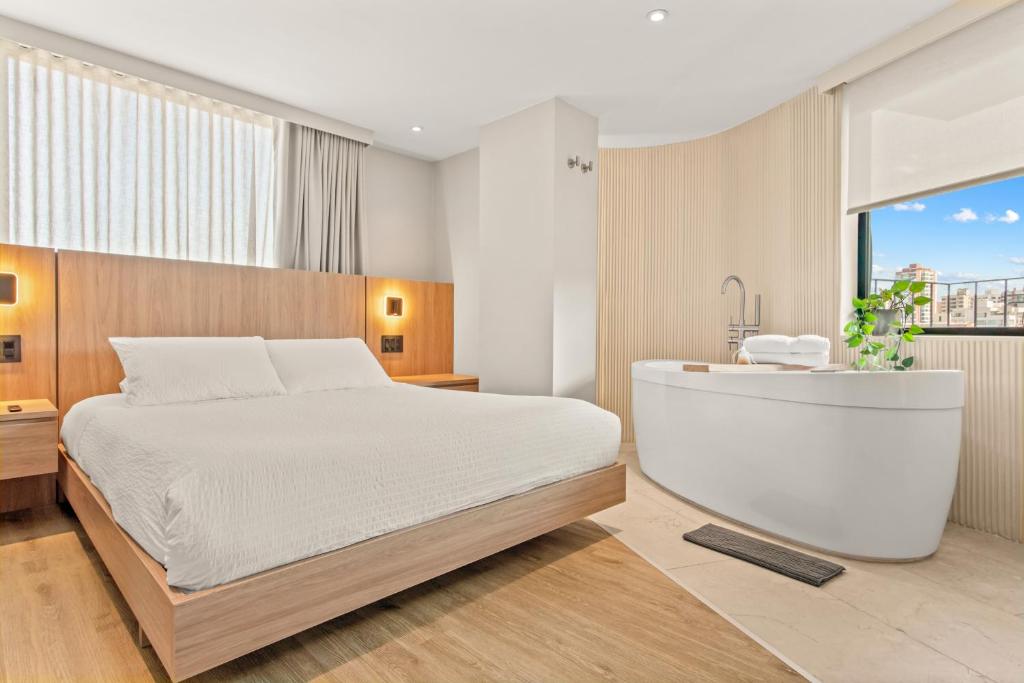 a bedroom with a white bed and a bath tub at Nodo Hotel in Manizales