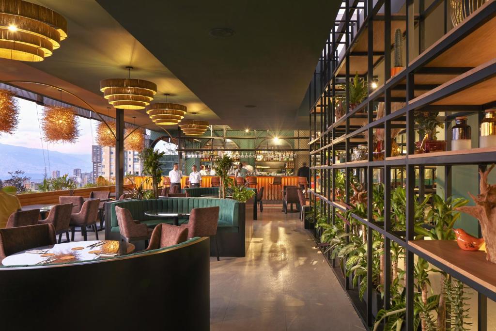 a restaurant with tables and chairs and plants at Blues Suites Medellín in Medellín