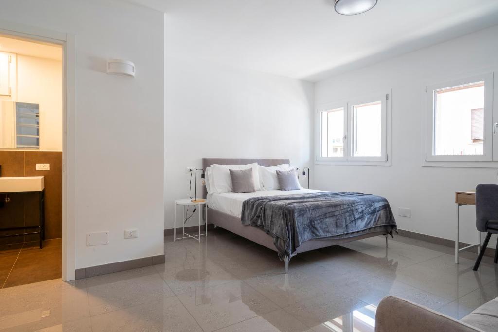 a white bedroom with a bed and two windows at Marghera Venice Link Rooms in Venice