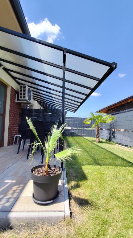 a patio with a black pergola and a plant at Ahoy Relax Apartmany Nesvady in Nesvady