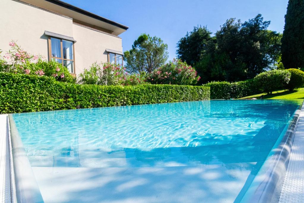 a swimming pool with blue water in front of a house at Casa di Giò Apartment, Pool, 200m from Lake Garda in Gardone Riviera