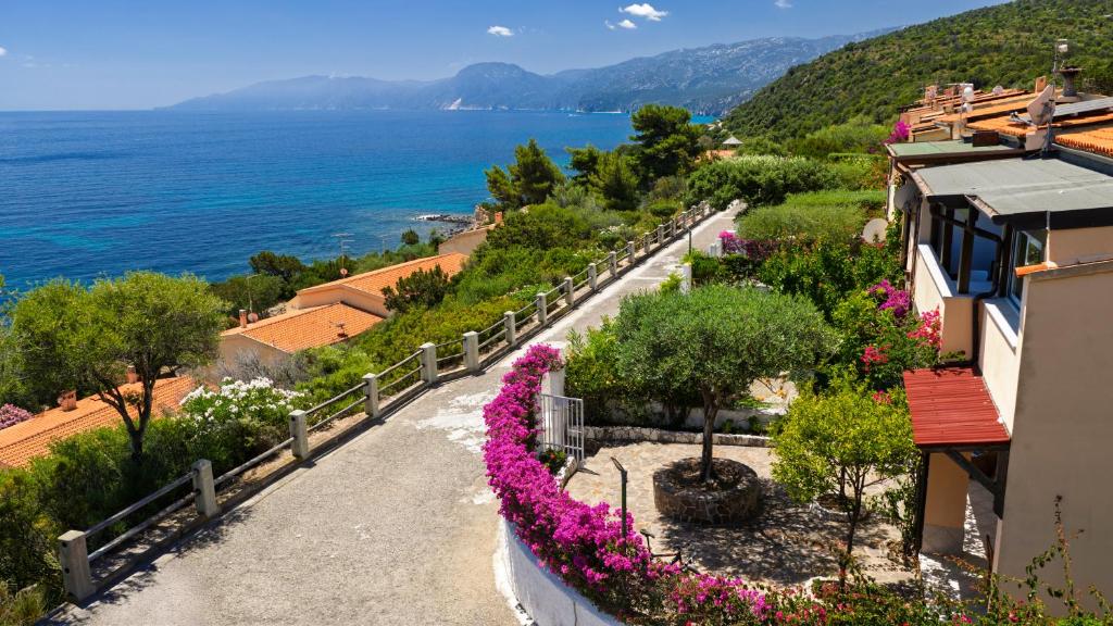 a view of the ocean from a hill with flowers at Sos Dorroles Motoparking in Cala Gonone