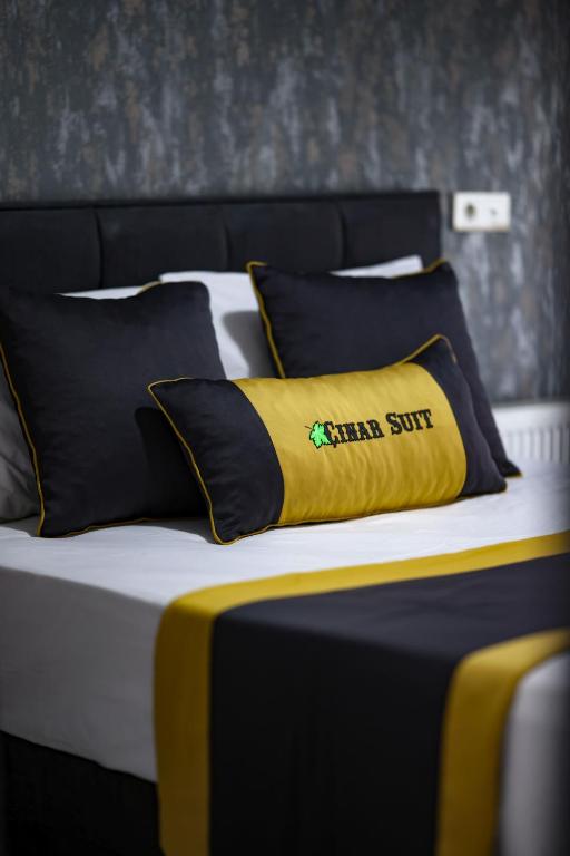 a bed with a yellow pillow on top of it at Çınar Suit Hotel in Buca