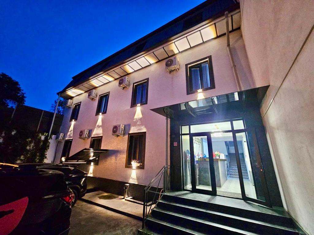 a building with a car parked in front of it at Aziza Hotel White Tashkent in Yakkasaray