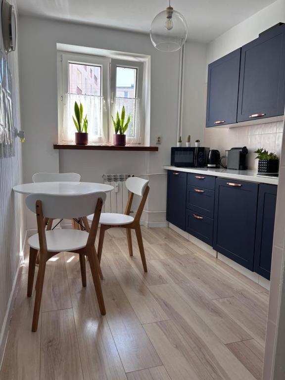 a kitchen with blue cabinets and a table and chairs at Apartament centrum Szczytno Mazury in Szczytno