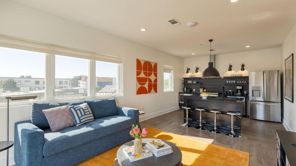a living room with a blue couch and a kitchen at The Carter by AvantStay in Nashville