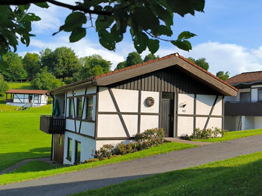 a small white building with a brown roof at Obergeschoss Bungalow 47 in der Ferienanlage RHÖN RESIDENCE in Dipperz