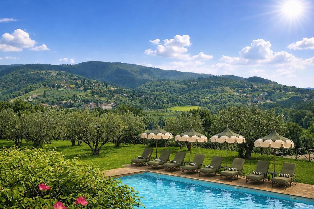 a pool with chairs and a view of a mountain at Borgo Tre Vaselle in Torgiano
