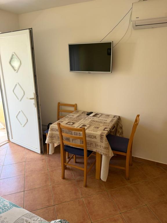 a dining room table with chairs and a tv on the wall at Villa Oliva Vir in Vir