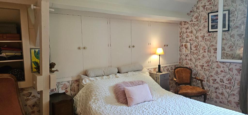 a bedroom with a white bed and a chair at Chambre d'hôtes Le Lupin Bleu in Saint-Coulomb