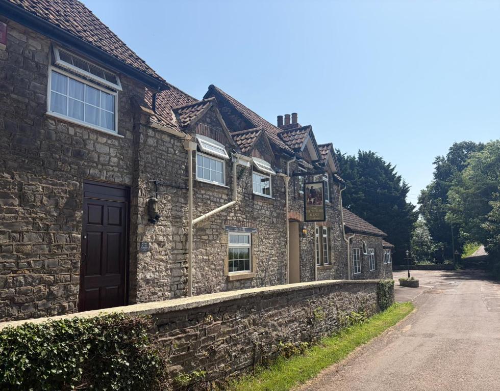 an old stone house with a stone wall at The Hunters Rest Inn in Clutton