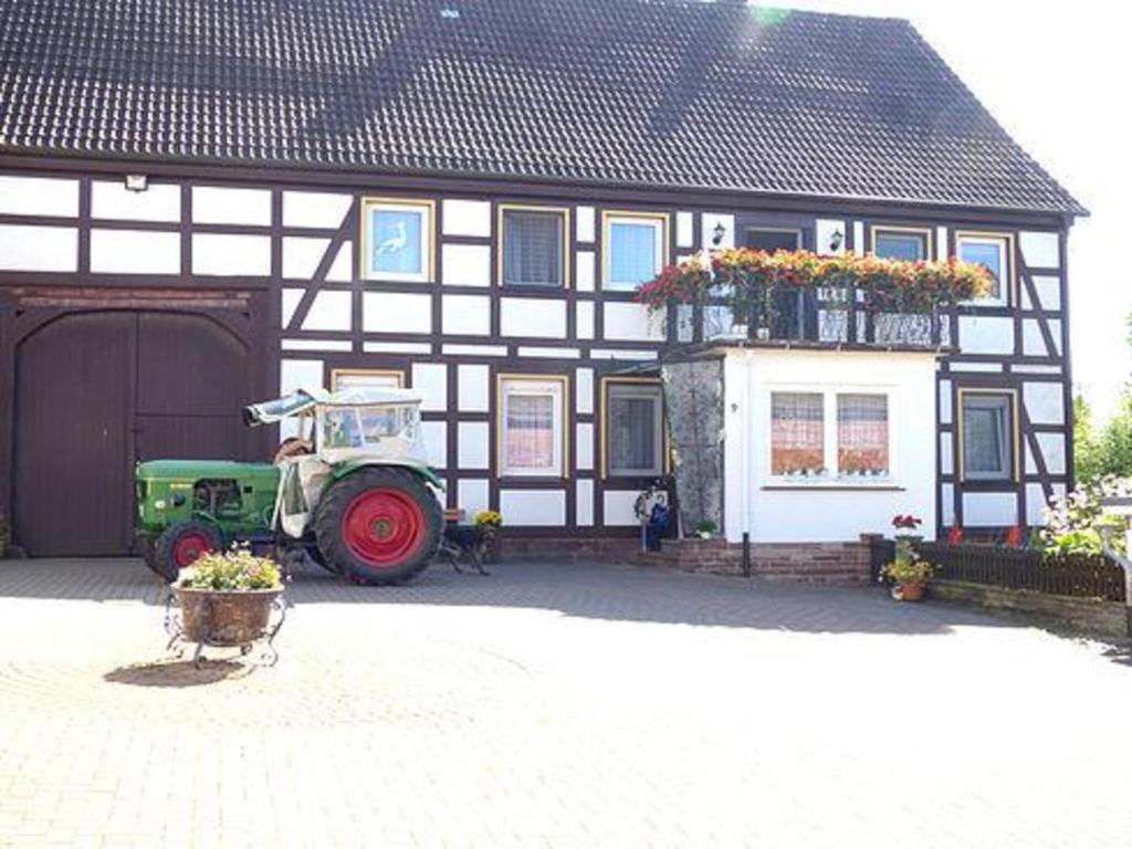 a tractor parked in front of a black and white building at Ferienhäuser Holenberg in Holenberg