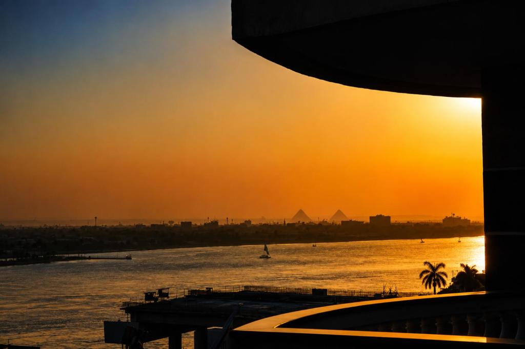 a sunset over the water with the pyramids in the background at Nile Pyramidal view place in Cairo