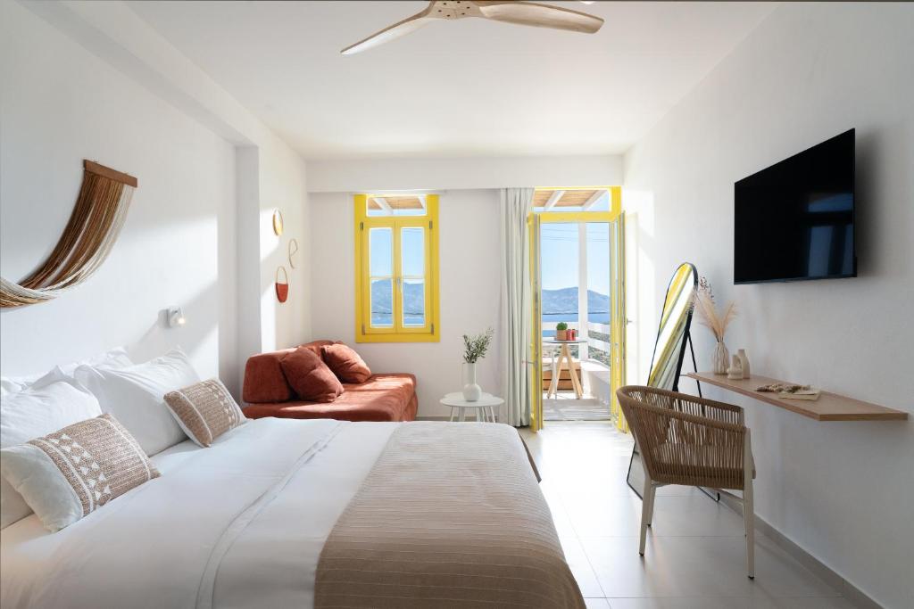 a white bedroom with a bed and a living room at Asterry Suites in Kimolos