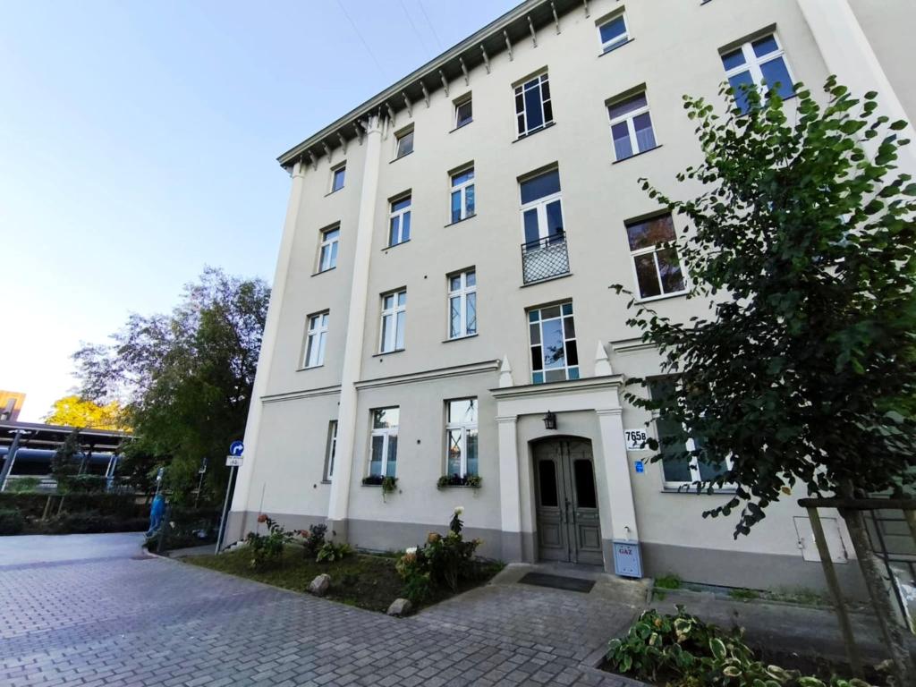 a large white building on a cobblestone street at Loft Hause Sopot in Sopot