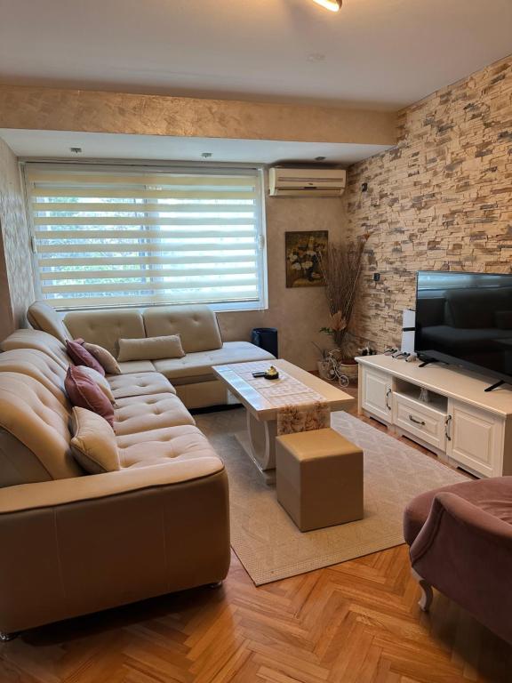 a living room with a couch and a television at Lux dvosoban stan u centru Bara in Bar