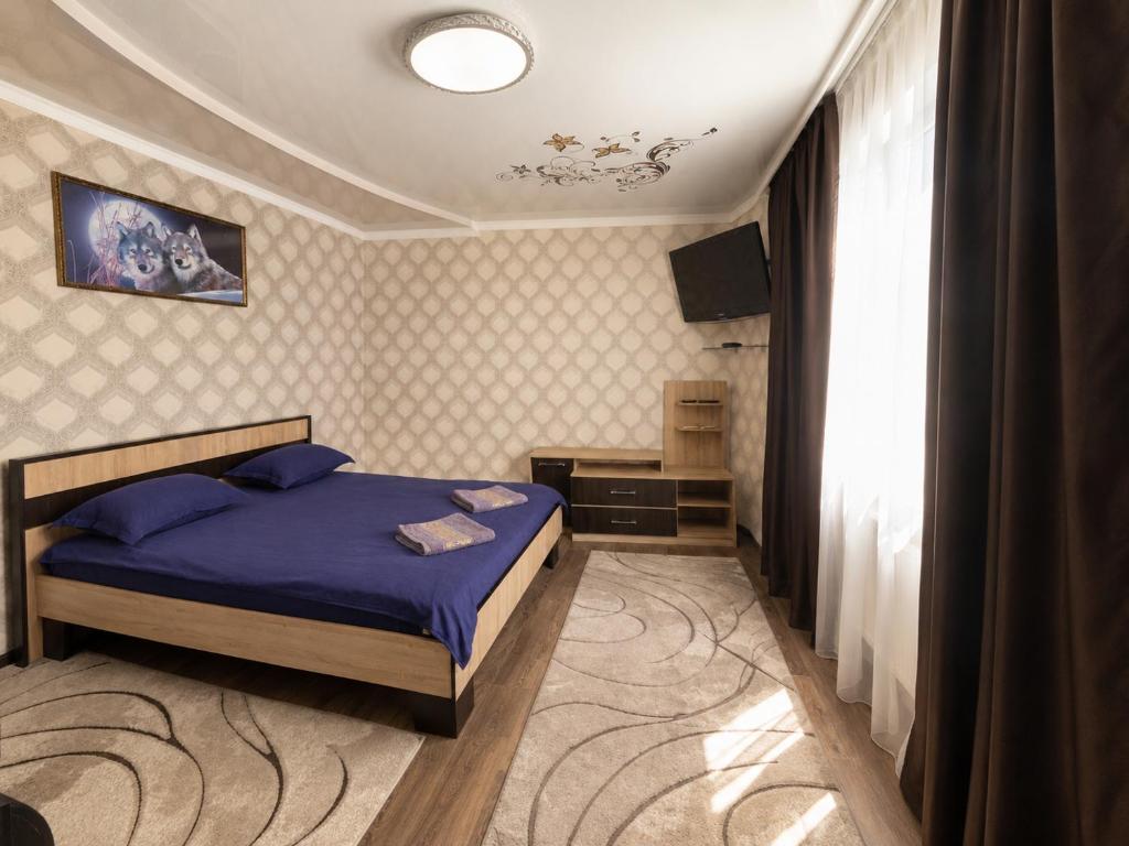 ein Schlafzimmer mit einem Bett und einem Fernseher in der Unterkunft Готель ВІОЛІТІ in Chmelnyzkyj