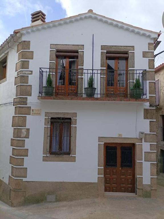 a white house with a balcony and two doors at Casa Villamiel in Villamiel