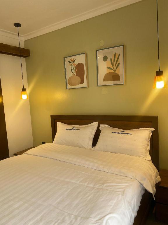a bedroom with a white bed with three pictures on the wall at Naigara hotel and suites in Kampala