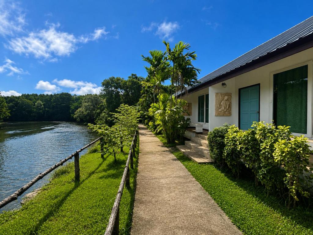 a walkway next to a building next to a river at Chaiyo Riverfront Resort Phuket in Phuket