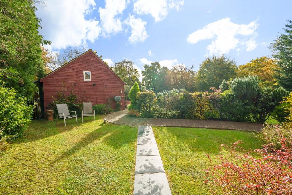 a garden with a red barn and a pathway at Studio Lodge in Crowhurst