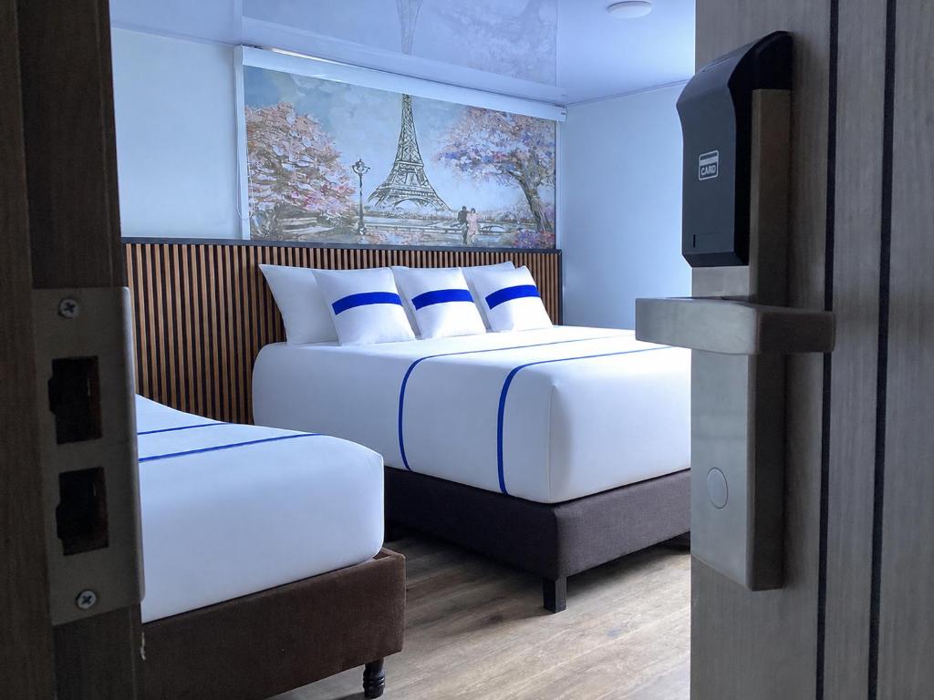 a bedroom with two beds and a picture of the eiffel tower at Paramount Hotel in Bogotá