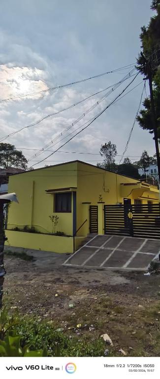 a yellow building with a parking lot in front of it at Sky park homestay in Yercaud