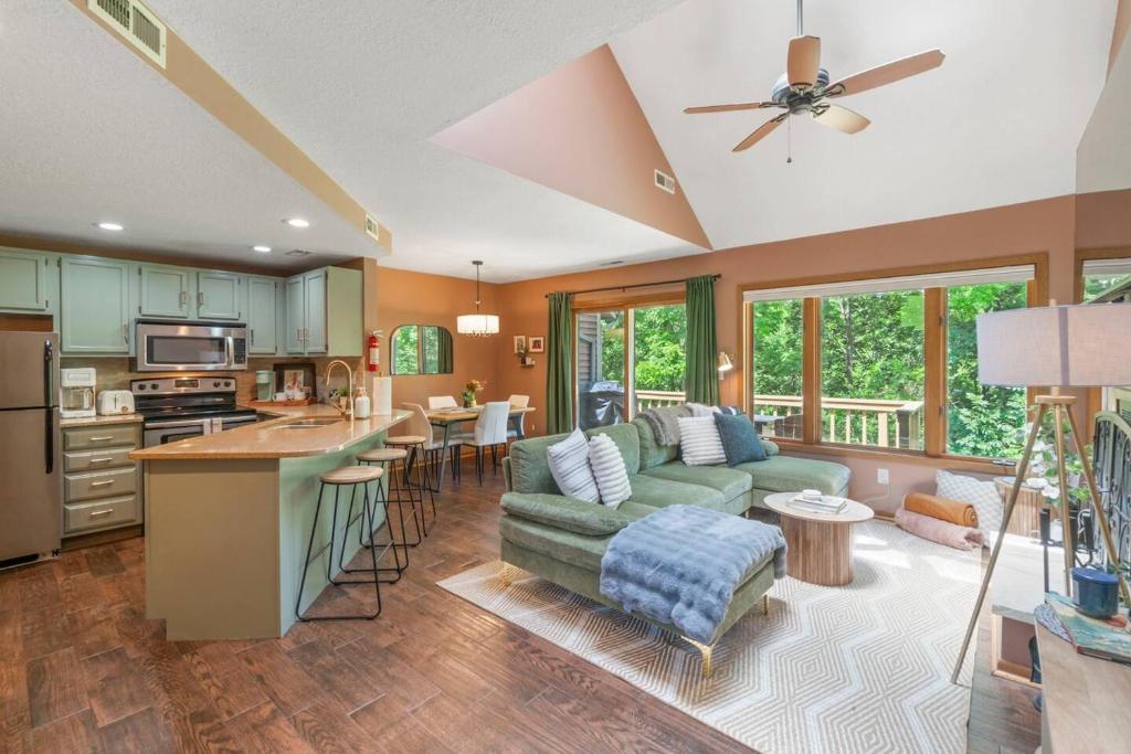 a living room with a green couch and a kitchen at King Bed Fire Pit Pool & Walk to North Course in Galena