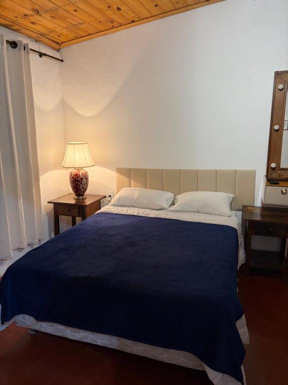 a bedroom with a large bed with a blue blanket at Aconchego Central in Tiradentes
