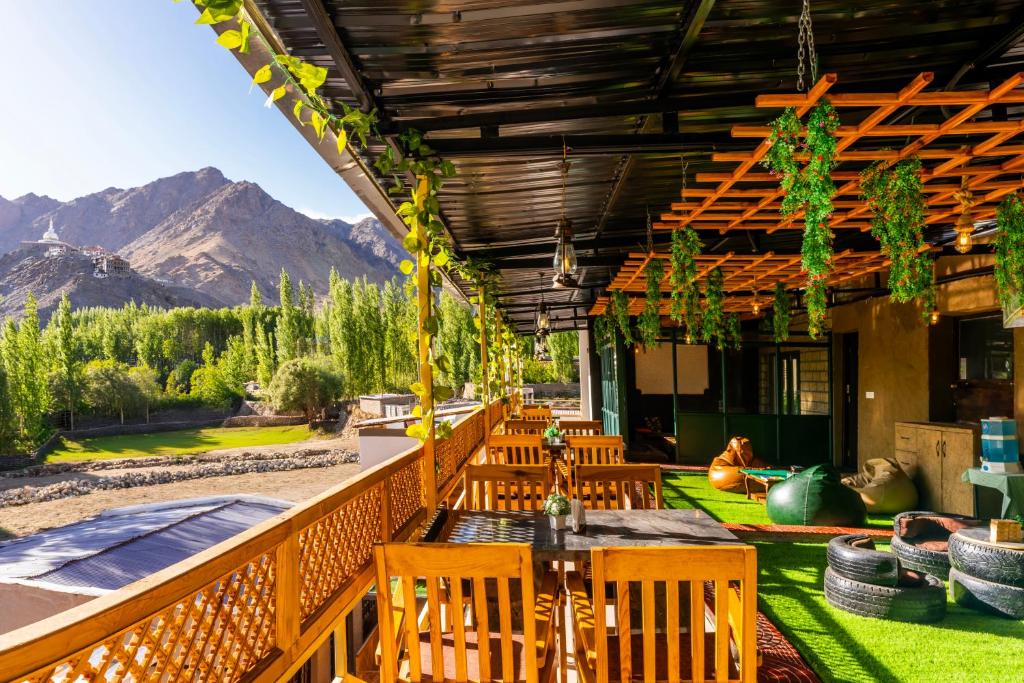 a patio with chairs and a table with mountains in the background at Rainbow Hostelier in Leh