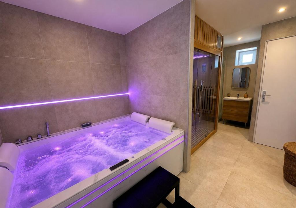 a bathroom with a large tub with purple lighting at Spa Privatif Montataire in Montataire