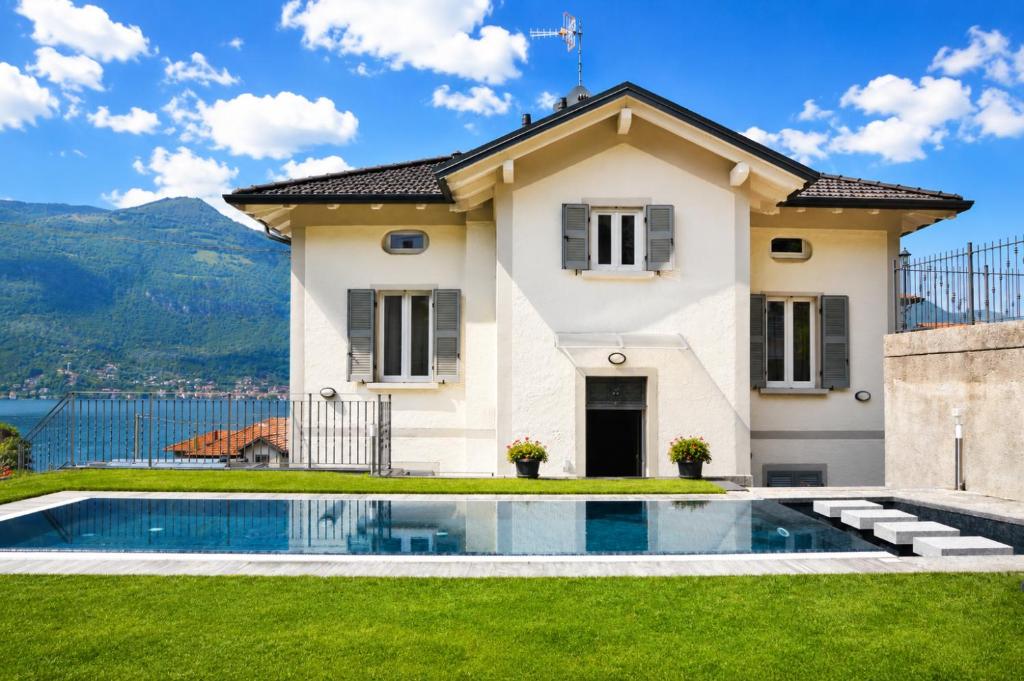 a villa with a swimming pool in front of a house at White suite - Jacuzzi, Swimming pool & Lake view in Lezzeno