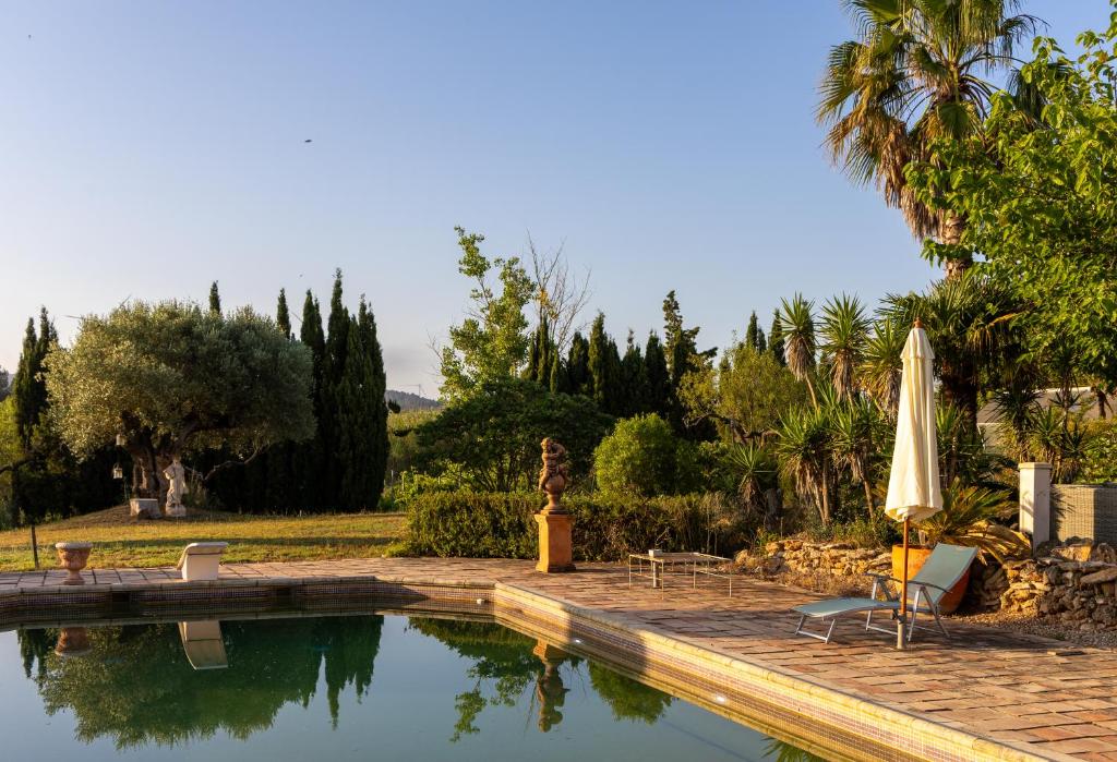 a swimming pool with an umbrella and a table and chairs at Ecolodge Carpe Diem El Perelló in Perelló