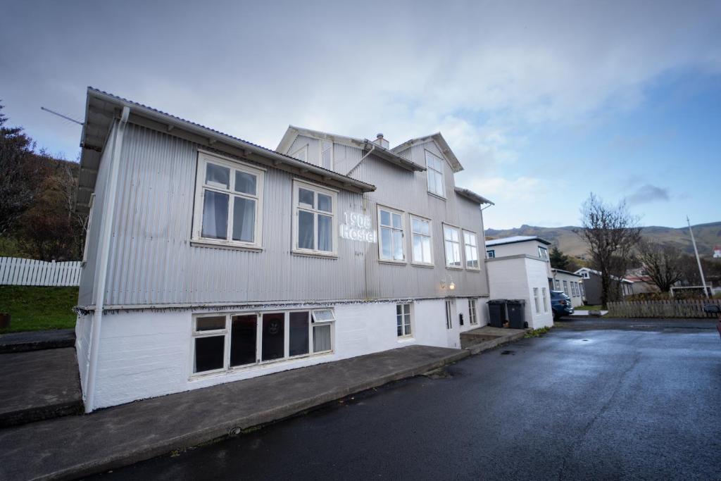 a white house sitting on the side of a street at 1908 Hostel by Tröll in Vík