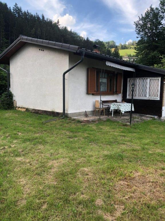 a small white house with a table in a yard at cozy alpine house in Breitenstein