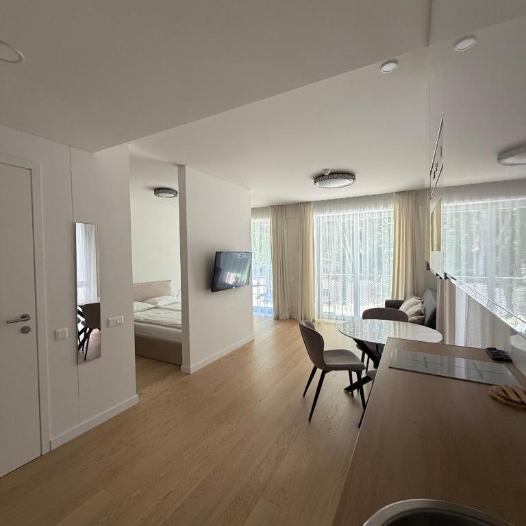 a living room with a table and a bedroom at Nerija in Juodkrantė