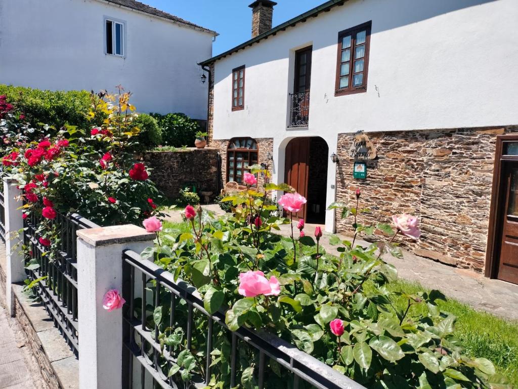 a garden in front of a white house with roses at Casa Benaxo Ribeira Sacra in Currelos