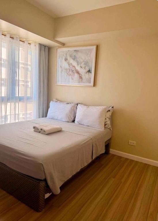 a bedroom with a bed with white sheets and a window at Avida Towers Riala Tower 1 in Cebu City