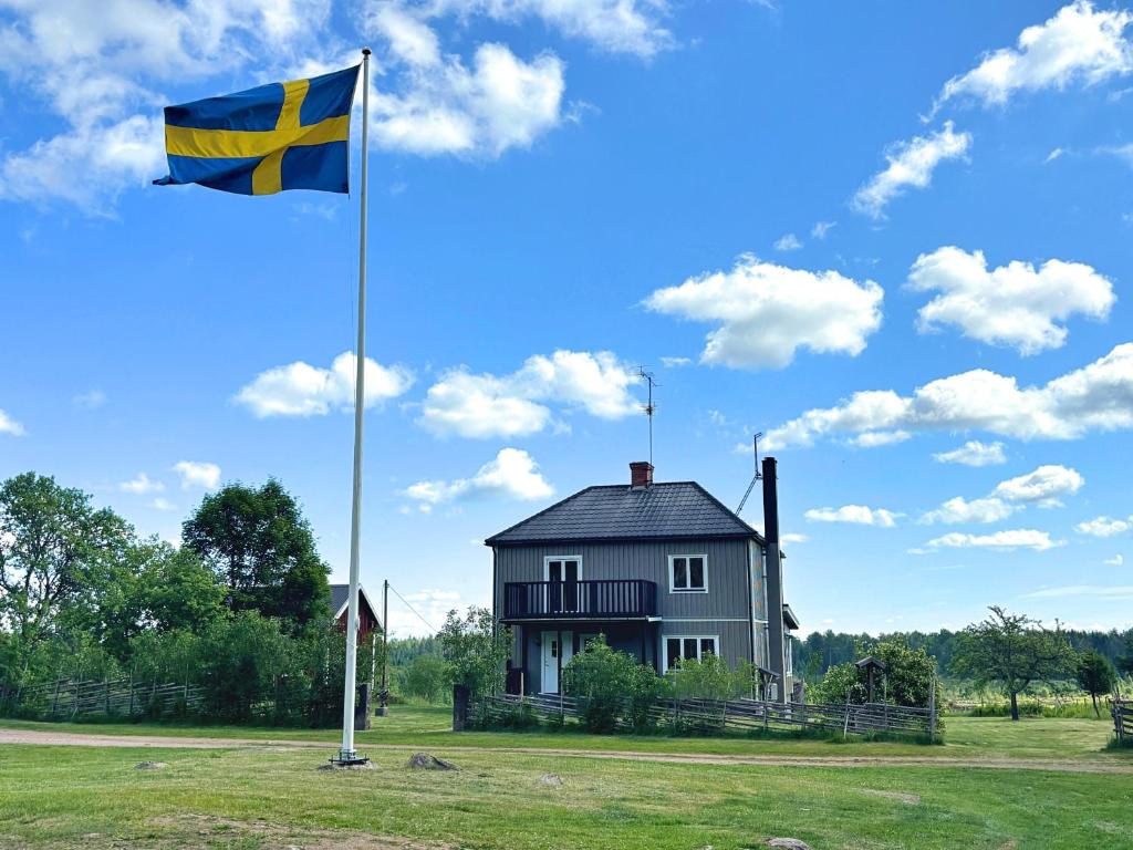 a flag in front of a house with a house at Hus Stora Hultet in Hultsfred