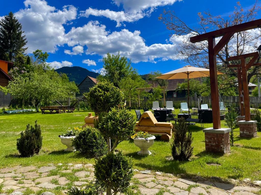 a garden with a couch and an umbrella at Pensiunea Anotimpuri Bran in Bran