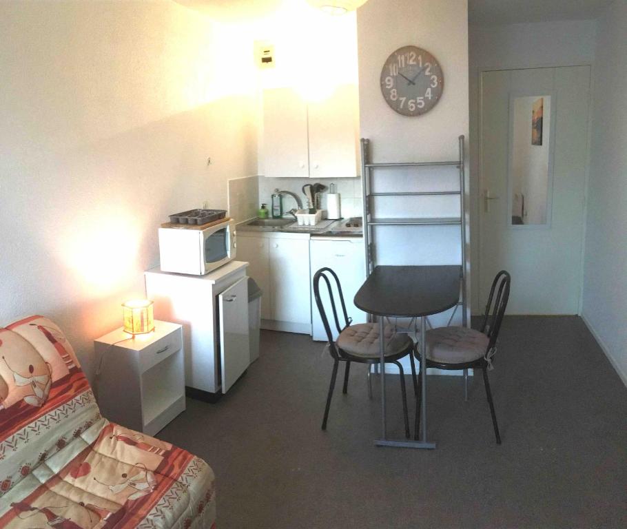 a living room with a table and chairs and a kitchen at Studio BRITTANY in Chambéry