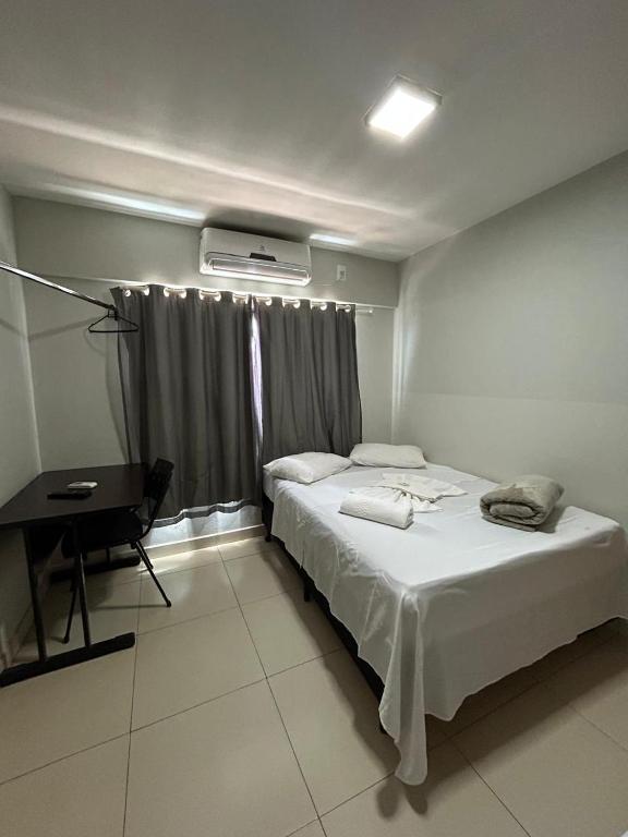 a bedroom with a bed and a desk and a window at Hotel 2001 in Iraí de Minas