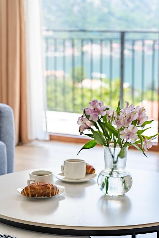 a table with two cups and a vase with flowers at Hill House Orahovac in Kotor